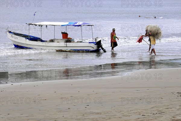 San Juan del Sur, Nicaragua, Fishermen on the beach hauling in fishing nets next to a boat, Central America, Central America