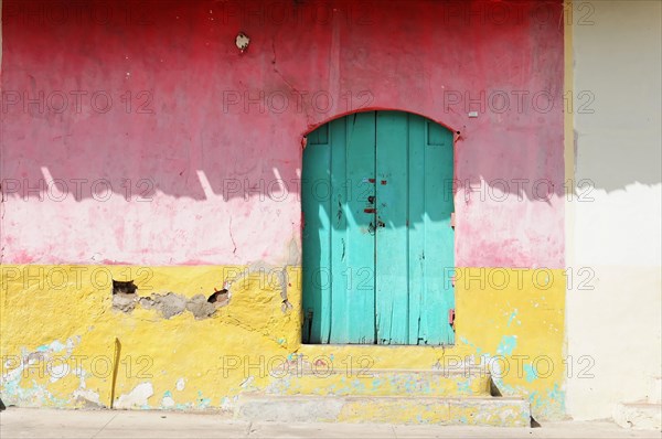 Granada, Nicaragua, A striking turquoise door embedded in a red, peeling wall, Central America, Central America