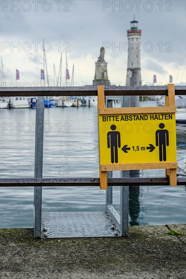 Advertising sign for physical distancing on the harbour railing in the old town of Lindau (Lake Constance), Bavaria, Germany, Europe