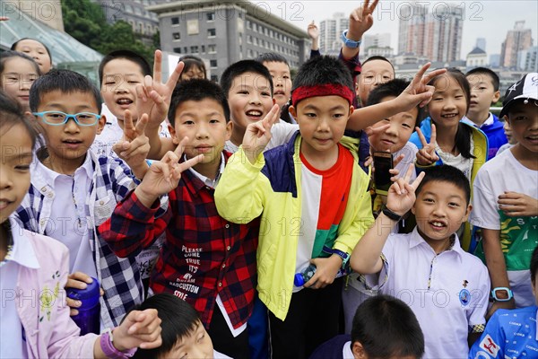 Chongqing, Chongqing Province, China, Asia, Group of students in colourful clothes show joyful gestures on a school trip, Asia