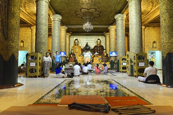 Shwedagon Pagoda, Yangon, Myanmar, Asia, Believers meditate in front of golden Buddha statues in a magnificent temple room, Asia