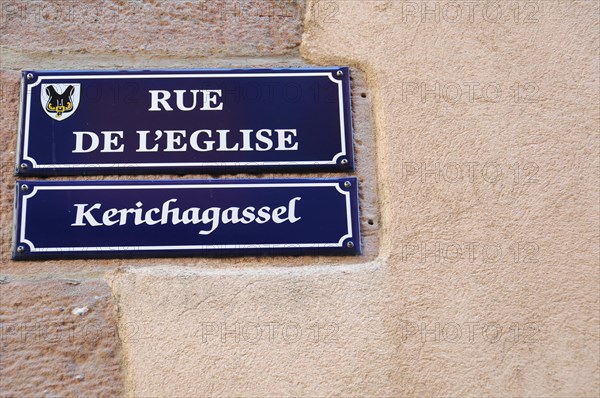 Kaysersberg, Alsace Wine Route, Alsace, Departement Haut-Rhin, France, Europe, Bilingual street signs on a stone wall with a coat of arms, Europe
