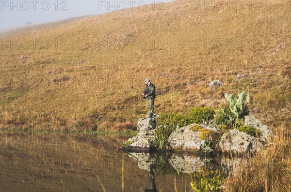 Sport fisherman fishing in lake on cloudy day, Cambara do sul, Rio Grande do sul, Brazil, South America