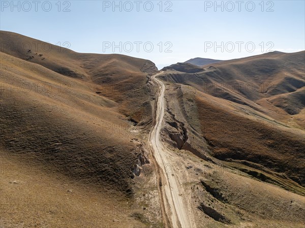 Moldo-Ashuu Pass, rutted road between yellow hills, near Baetov, Naryn region, Kyrgyzstan, Asia