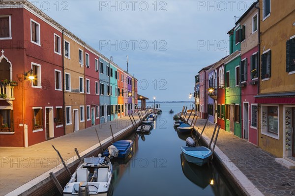 Moored boats on canal lined with colourful stucco houses and shops at dusk, Burano Island, Venetian Lagoon, Venice, Veneto, Italy, Europe