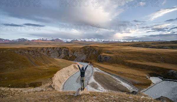 Tourist stretching his arms in the air, mountain valley with Sary Jaz river, high glaciated mountain peaks of the Tien Shan in the background, autumn mountains with yellow grass, Tien Shan, Kyrgyzstan, Asia