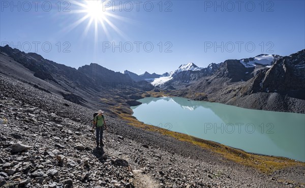Mountaineers on the way to the Ala Kul Pass, turquoise Ala Kul mountain lake in the morning light, Sun Star, Tien Shan Mountains, Kyrgyzstan, Asia