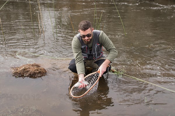 Fisherman fly fishing rainbow trout on mountain in beautiful scenery