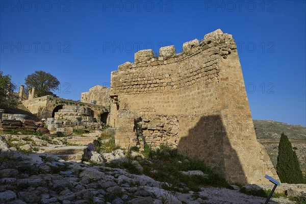 Stone ruins under a bright blue sky with sparse vegetation in the foreground, St John's Fortress, Lindos, Rhodes, Dodecanese, Greek Islands, Greece, Europe