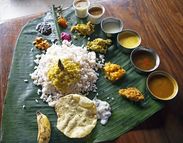 Sadya or variety of traditional vegetarian dishes served for lunch on a banana leaf, Kerala, India, Asia