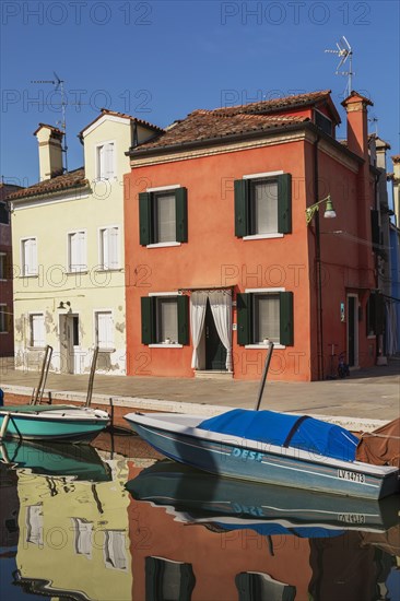 Moored boats on canal lined with red and yellow stucco houses, Burano Island, Venetian Lagoon, Venice, Veneto, Italy, Europe