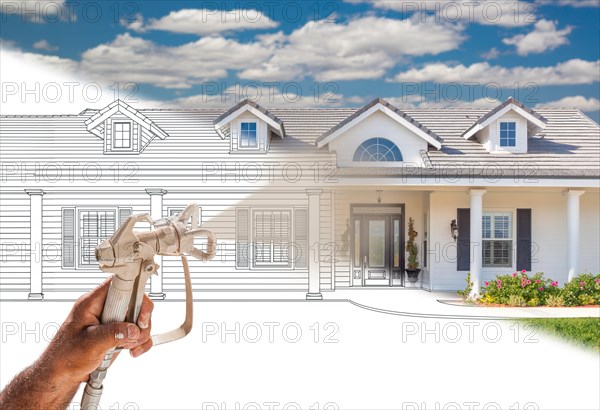 Professional spray painter holding spray gun spraying new house over design drawing