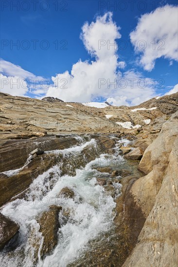 A littel stream flowing down the mountains from Wasserfallwinkelkeesee in summer on a sunny day, Kaernten, Austria, Europe