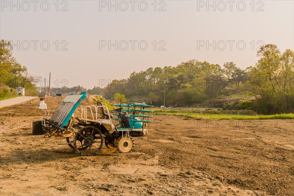 Rice paddy planting vehicle sitting in dirt field in countryside under a gray morning sky in South Korea
