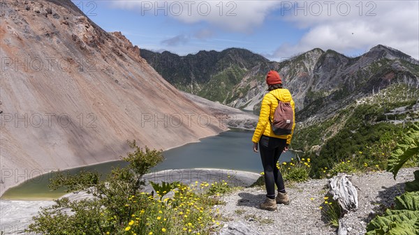 Young woman in yellow jacket standing in front of a volcano, Chaiten Volcano, Carretara Austral, Chile, South America