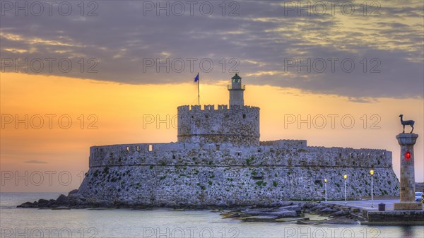 A castle by the sea with a breathtaking sunset in the background, sunrise, dawn, Fort of Saint Nikolaos, lighthouse, European roe deer statue, harbour promenade, Rhodes, Dodecanese, Greek Islands, Greece, Europe