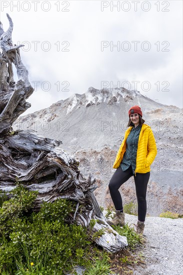 Young woman in yellow jacket standing in front of a volcano, Chaiten Volcano, Carretara Austral, Chile, South America