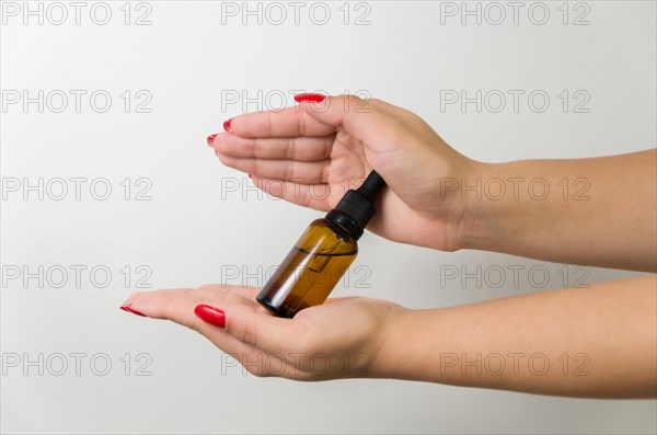 Product package with serum and a woman hand in studio on a background to promote an antiaging treatment. Skincare, beauty and bottle with a female model. Mockup