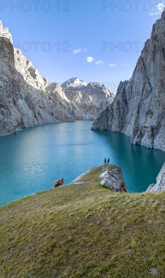 Two hikers, turquoise mountain lake Kol Suu with rocky steep mountains, Kol Suu Lake, Sary Beles Mountains, Naryn Province, Kyrgyzstan, Asia