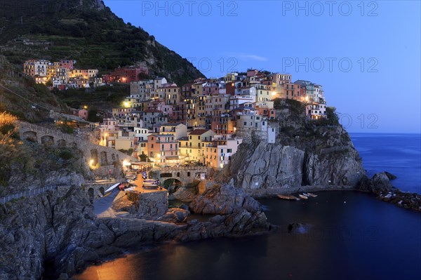 A Mediterranean village on the coast is romantically illuminated by the sea at nightfall, Italy, Liguria, Manarola, Riomaggiore, La Spezia Province, Cinque Terre, Europe