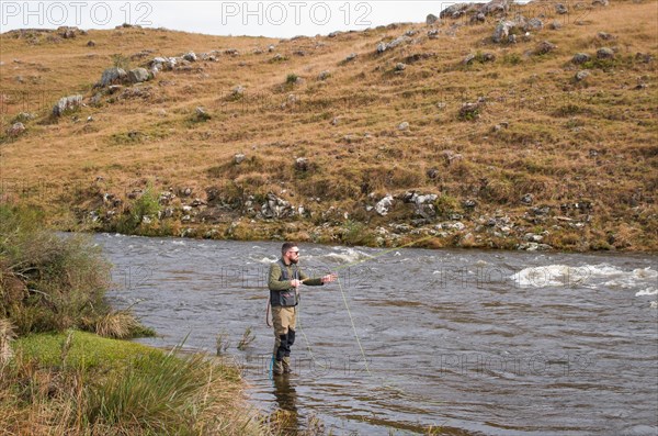 Fisherman fly fishing rainbow trout on mountain in beautiful scenery