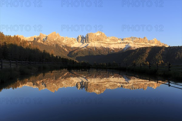 The last rays of the day illuminate the mountains reflected in a calm lake, Trentino-Alto Adige, Alto Adige, Bolzano province, Dolomites, Reflection rose garden at Wuhnleger Lake, San Cipriano