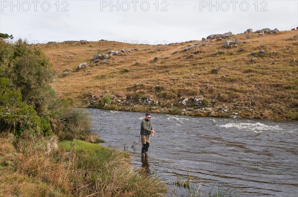 Fisherman fly fishing rainbow trout on mountain in beautiful scenery