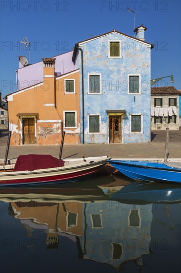 Moored boats on canal lined with orange, mauve and blue stucco houses, Burano Island, Venetian Lagoon, Venice, Veneto, Italy, Europe