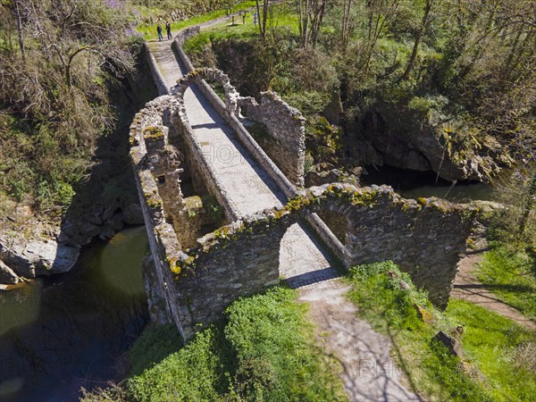 Ruins of a historic bridge with moss-covered stones over a river in a green landscape, Bridge of the Devil, Pont de Diable, Romanesque stone bridge, Ariege river, Montoulieu, Ariege, France, Europe