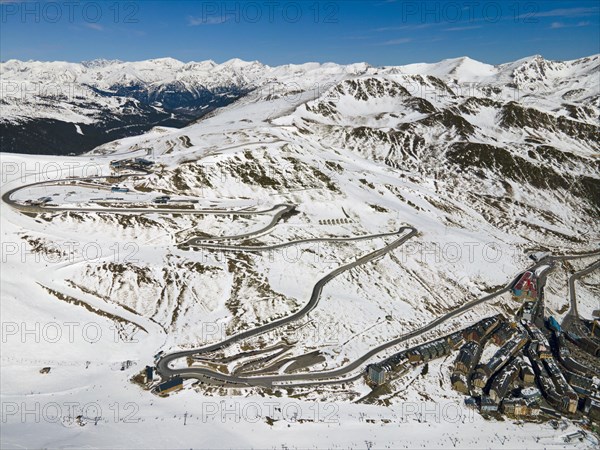 Snow-covered mountain landscape with serpentine road and settlement from a bird's eye view, serpentine road near El Pas de la Casa, Encamp, Andorra, Pyrenees, Europe