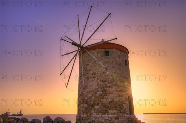 Historic windmill against a purple-orange coloured sunrise sky by the sea, twilight, Mandraki Oat, Rhodes, Dodecanese, Greek Islands, Greece, Europe