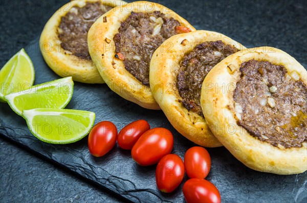 Delicious Lebanese (Arabic) food, genuine sfihas on a slate plate with tomatoes and lemons