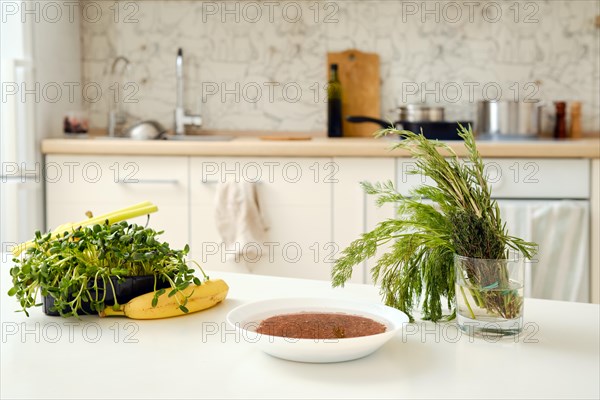 Fresh vegetables, herbs and fruits and a bowl with soaked rice on a kitchen table
