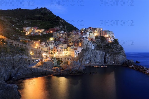 Nocturnal atmosphere over a quiet coastal town with shining windows and calm sea, Italy, Liguria, Manarola, Riomaggiore, La Spezia Province, Cinque Terre, Europe