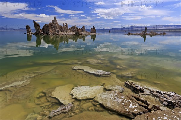 Limestone tufa structures protrude into a lake with clear water and a cloudy sky, Mono Lake, North America, USA, South-West, California, California, North America