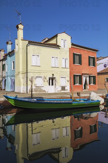 Moored green and blue boat on canal lined with yellow and red stucco houses, Burano Island, Venetian Lagoon, Venice, Veneto, Italy, Europe
