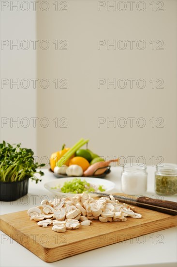 Kitchen table with chopped mushrooms and fresh vegetables