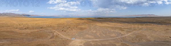 Road and off-road vehicle, Aerial view, Vast empty landscape at the mountain lake Song Kul in autumn, Moldo Too Mountains, Naryn region, Kyrgyzstan, Asia