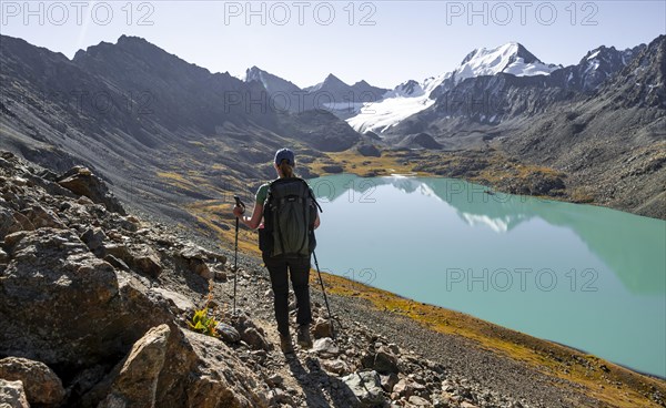 Trekking, hiker in the Tien Shan high mountains, mountain lake Ala-Kul Lake, 4000 metre peak with glacier, Ak-Su, Kyrgyzstan, Asia