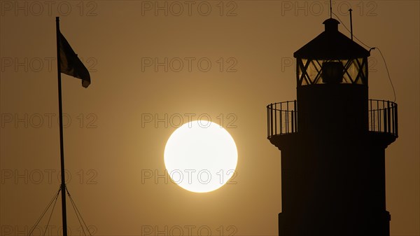 Silhouette of a lighthouse in front of an Orange coloured sky at sunrise, sunrise, dawn, Fort of Saint Nikolaos, harbour promenade, Rhodes, Dodecanese, Greek Islands, Greece, Europe
