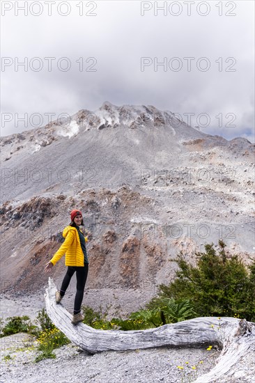 Young woman in yellow jacket standing in front of a volcano, Chaiten Volcano, Carretara Austral, Chile, South America