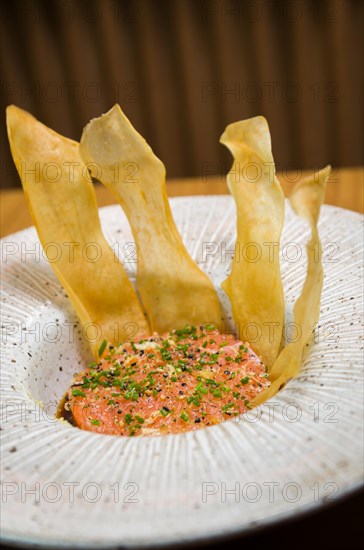 PERUVIAN FOOD. Spiced Salmon Ceviche with Chives and Lime on a white plate served with Fried Sweet Potato Wedges