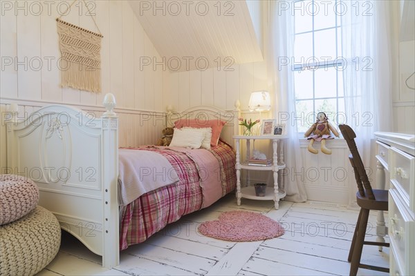 Single bed with red, pink and grey tartan bedspread, white painted antique style wooden headboard and footboard, nightstand, dresser with brown chair in a kid's bedroom with white painted larch wood floorboards on upstairs floor inside country style home, Quebec, Canada, North America