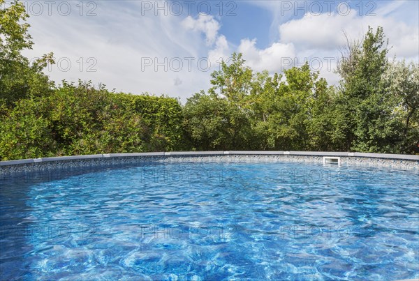 Above ground swimming pool surrounded by deciduous trees in residential backyard, Quebec, Canada, North America