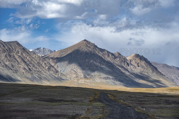 Gravel track on plateau, dramatic high mountains, Tian Shan Mountains, Jety Oguz, Kyrgyzstan, Asia