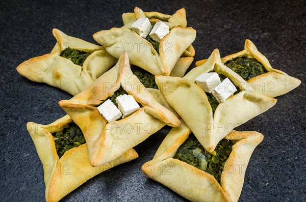 Delicious Lebanese (Arabic) food, spinach sfiha with ricotta cheese on black stone background