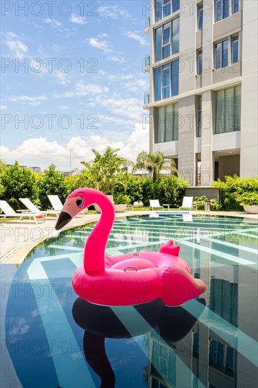 A pink flamingo pool float is floating in a pool. Vertical shot
