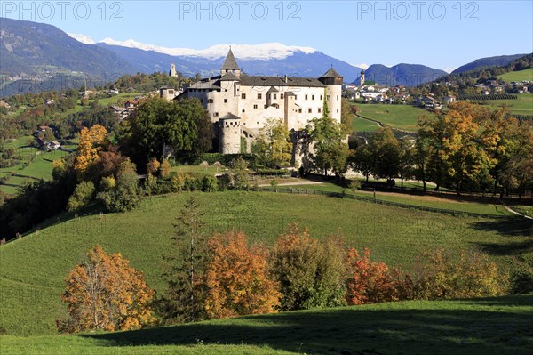 A castle surrounded by autumn trees and green meadows against a mountain background, Italy, Trentino-Alto Adige, Alto Adige, Bolzano province, Dolomites, Proesels Castle, Europe