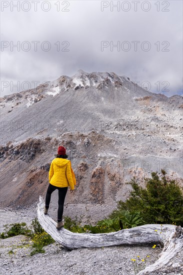 Young woman in yellow jacket standing in front of a volcano, Chaiten Volcano, Carretara Austral, Chile, South America