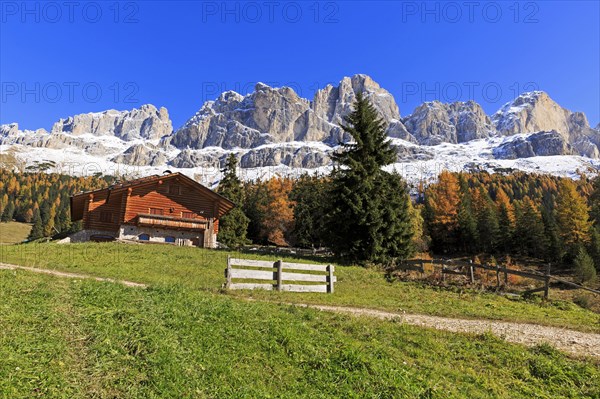 Wooden log cabin with a bench in front of it, surrounded by autumn coloured mountains, Italy, Alto Adige, Bolzano province, Dolomites, rose garden, Europe